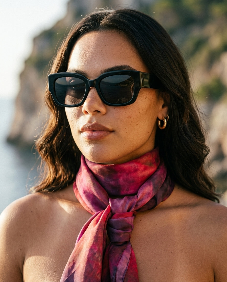 Ember Square Silk Scarf (Resonant Bloom Edition) styled as a front knot by a model, showing the fluid drape and colour gradient of crimson, magenta and deep plum on silk habotai.