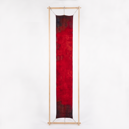 Ember Wool-Silk Scarf (Resonant Bloom Edition) stretched on a vertical timber frame against a white background, showing the full 30x180cm artwork in crimson, maroon and charcoal.