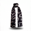 Premium long silk wool blend scarf, measuring 30x180cm, in the "Tectonic Monochrome" design, featuring a bold abstract graphic pattern of dark grey and deep black shapes, styled in an upright wrap format against a clean white background.