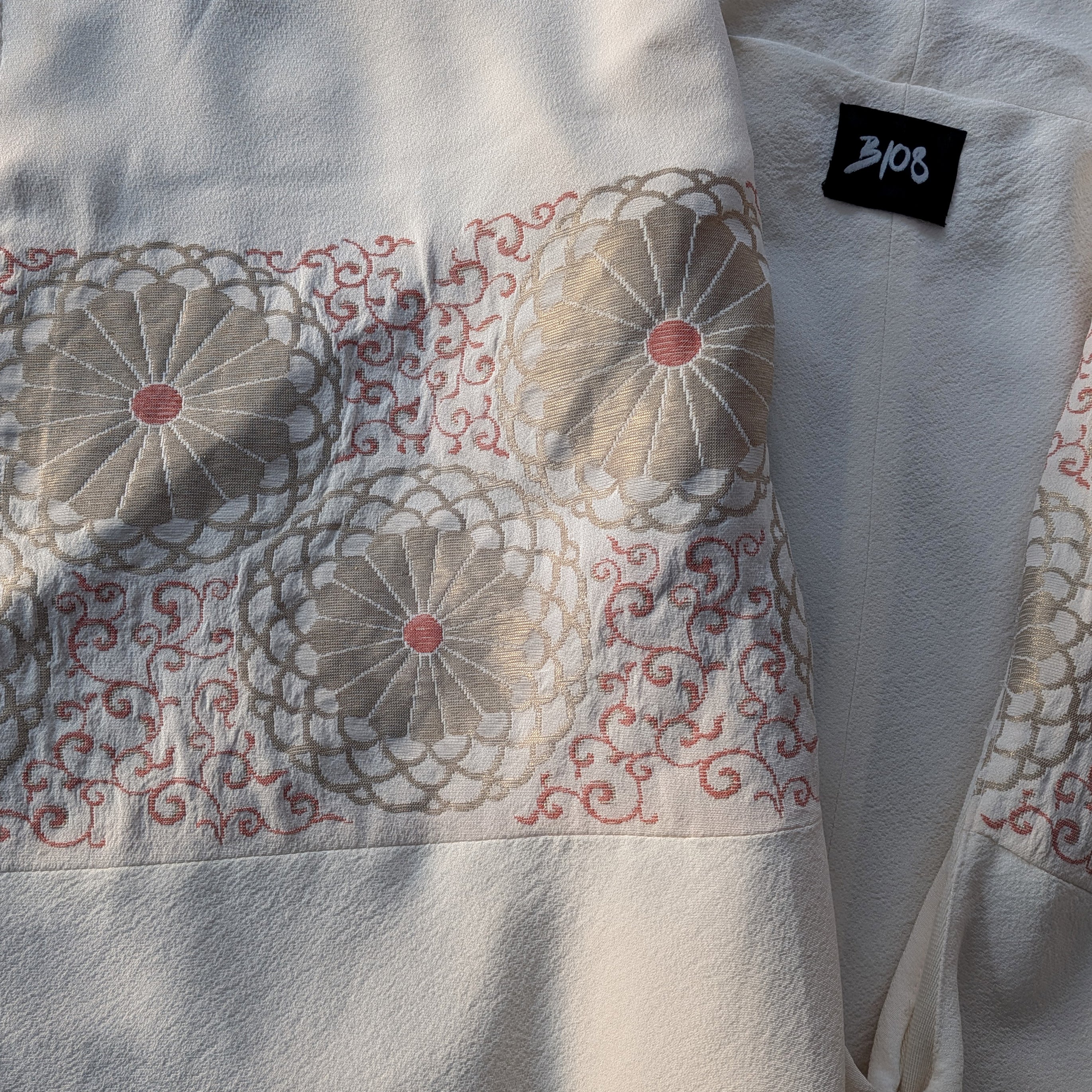 Macro texture detail highlighting the upcycled Japanese kimono silk lining pattern, un-dyed cream merino wool weave, and black B108 brand label.
