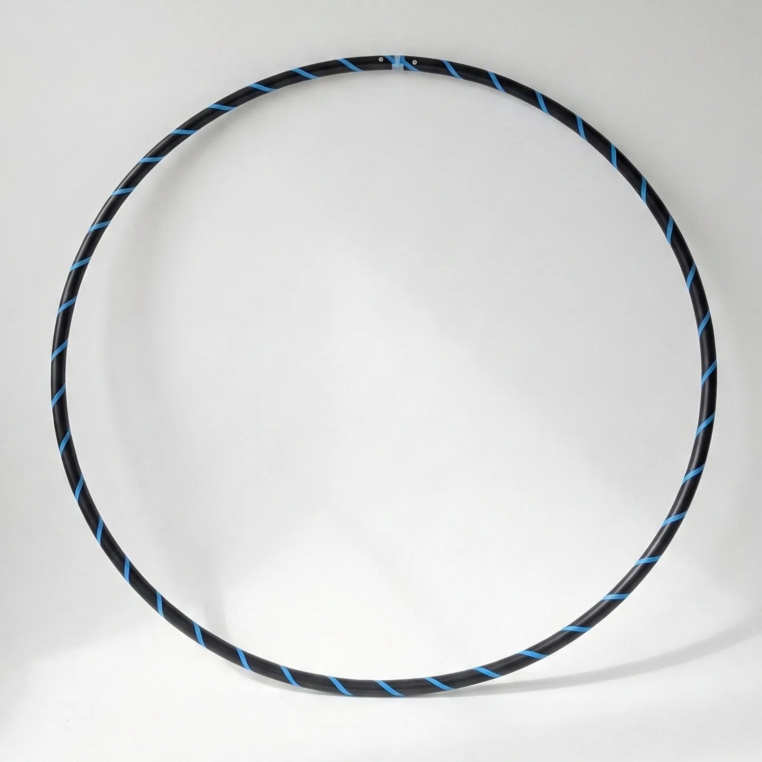 Studio shot of the B108 DESIGN Archival Dance Hoop in Blueberry Bliss featuring a blue and black spiral grip tape pattern against a white backdrop.