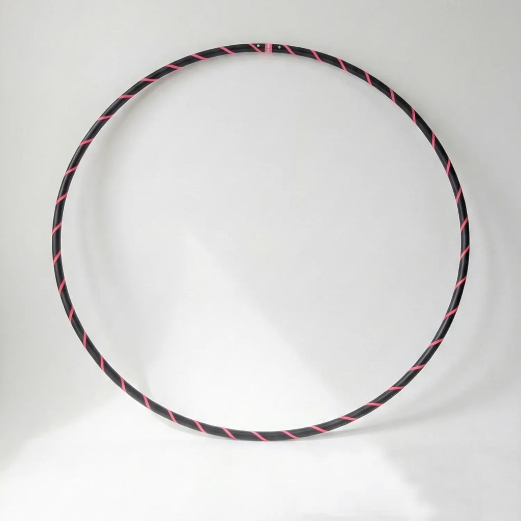 Studio shot of the B108 DESIGN Archival Dance Hoop in Pink Panther featuring a fluoro pink and black spiral grip tape pattern against a white backdrop.