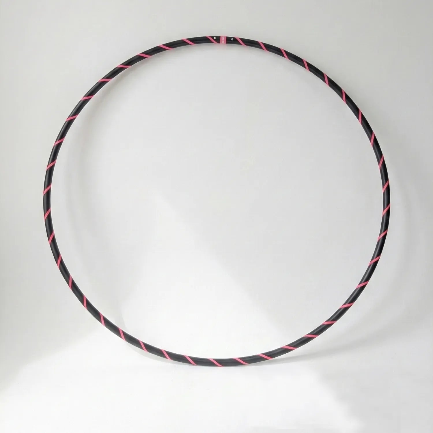 Studio shot of the B108 DESIGN Archival Dance Hoop in Pink Panther featuring a fluoro pink and black spiral grip tape pattern against a white backdrop.
