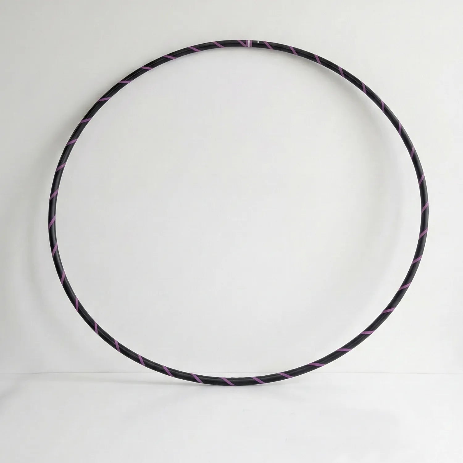 Studio shot of the B108 DESIGN Archival Dance Hoop in Midnight Violet featuring a purple and black spiral grip tape pattern against a white backdrop.
