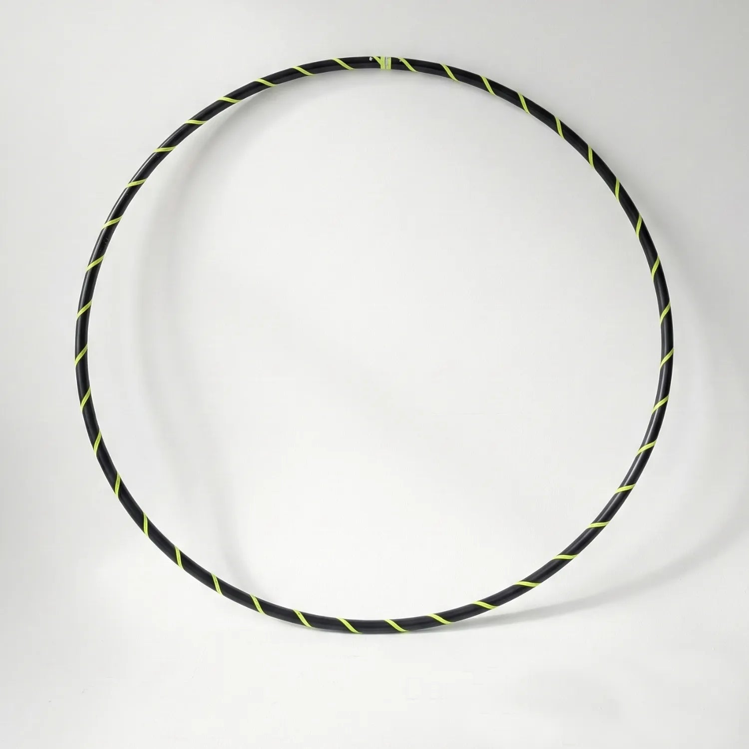 Studio shot of the B108 DESIGN Archival Dance Hoop in Electric Bee featuring a fluoro yellow and black spiral grip tape pattern against a white backdrop. 