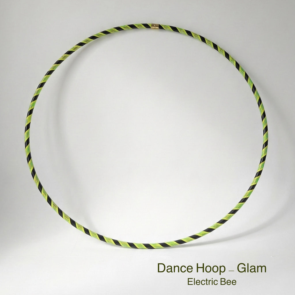 Dance hula hoop – Electric Bee Glam Edition. Professional black tubing featuring a reflective yellow and fluoro yellow grip tape spiral design for dance and fitness.