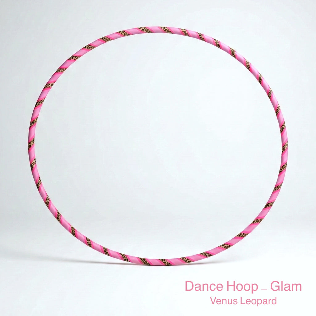 A professional Dance Hoop – Glam in the Venus Leopard style, featuring a vibrant pink and leopard print spiral tape pattern. The hoop is set against a minimalist white background. Text at the bottom right corner reads: Dance Hoop – Glam Venus Leopard.