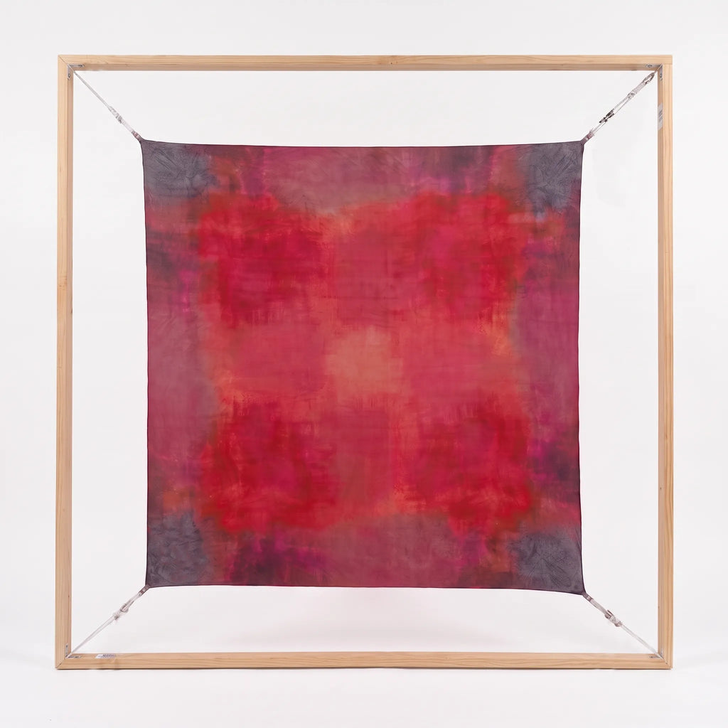 Full view of the square Ember luxury silk Habotai scarf by B108 Design displayed flat within a square wooden frame, showing the hand-dyed crimson, magenta, and plum gradient pattern.