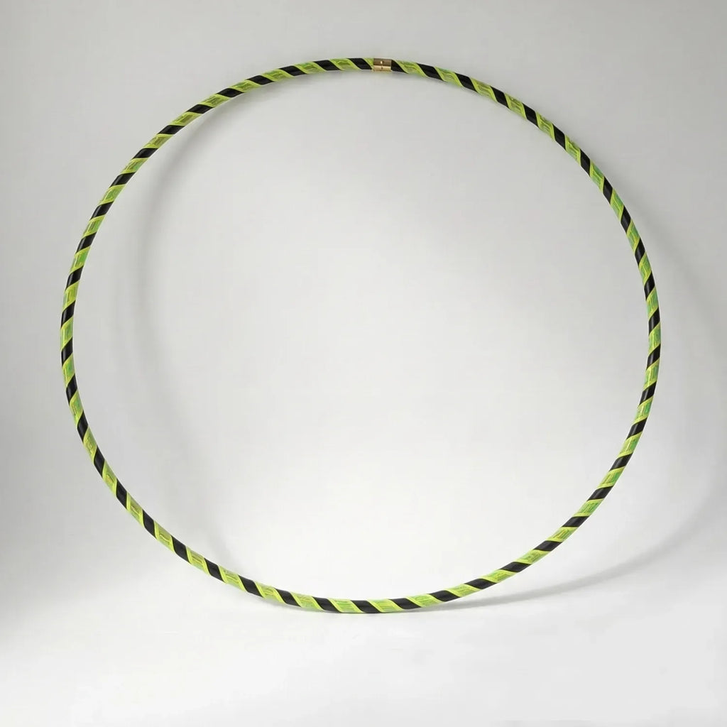 Studio shot of the B108 DESIGN Archive Glam Dance Hula Hoop in Electric Bee, featuring a bright lime green and black spiral grip tape pattern against a white backdrop. 