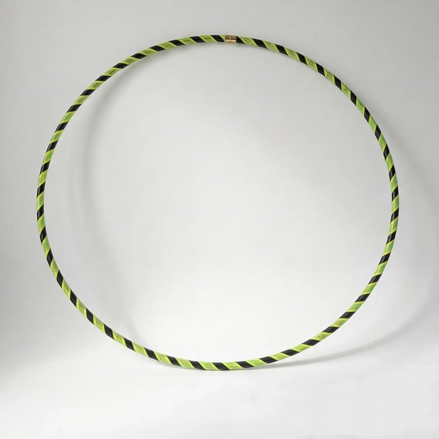 Studio shot of the B108 DESIGN Archive Glam Dance Hula Hoop in Electric Bee, featuring a bright lime green and black spiral grip tape pattern against a white backdrop. 