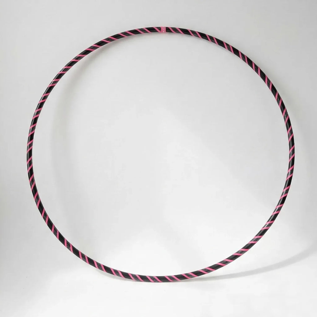 Studio shot of the B108 DESIGN Archive Glam Dance Hula Hoop featuring a vibrant pink and black spiral grip tape pattern against a clean white backdrop.