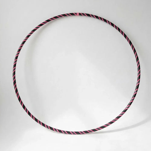Studio shot of the B108 DESIGN Archive Glam Dance Hula Hoop featuring a vibrant pink and black spiral grip tape pattern against a clean white backdrop.