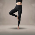 Model performing a tree pose in high-waisted black hemp organic cotton movement leggings and matching crop top by B108 DESIGN.