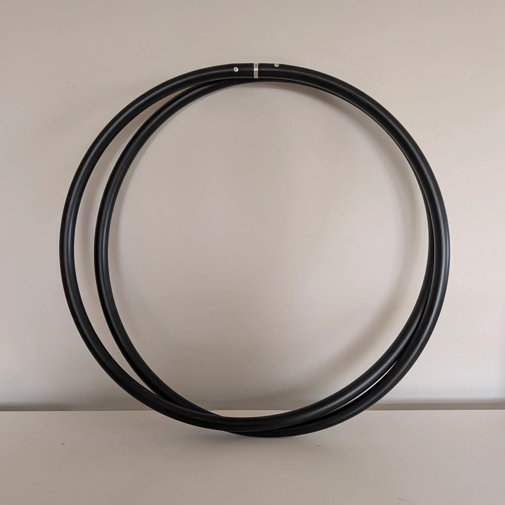 Studio shot of the Recycled Polymer Dance Hoop by B108 DESIGN coiled down to half its size for travel and storage against a neutral off-white background.