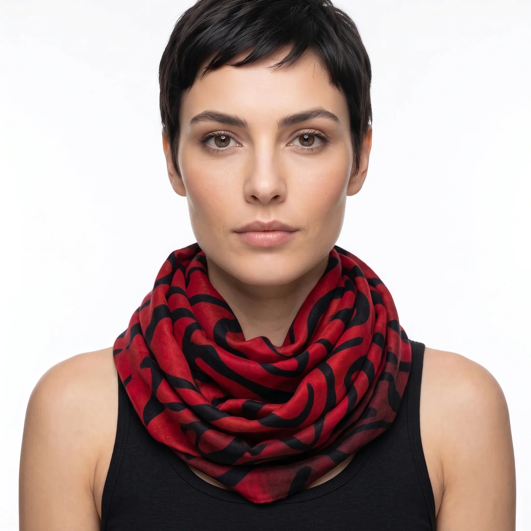 Studio portrait of a model wearing the Tectonic Ember luxury silk-wool scarf by B108 Design wrapped loosely around the neck, highlighting the vibrant red and black abstract pattern.