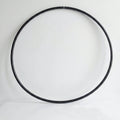 Studio shot of the B108 DESIGN weighted fitness hula hoop in obsidian black leaning against a white wall.