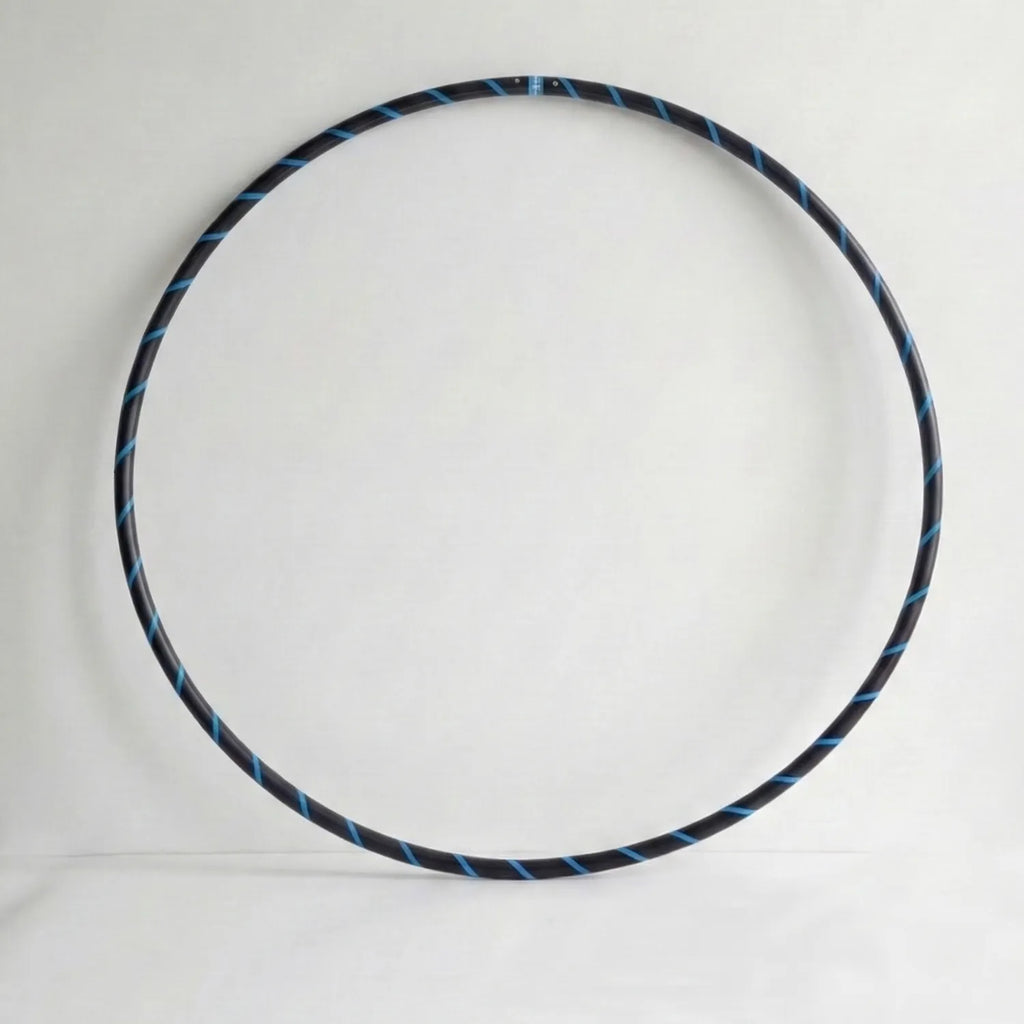 Studio shot of the B108 DESIGN weighted fitness hula hoop in obsidian black with an electric blue spiral grip tape pattern against a clean white backdrop.