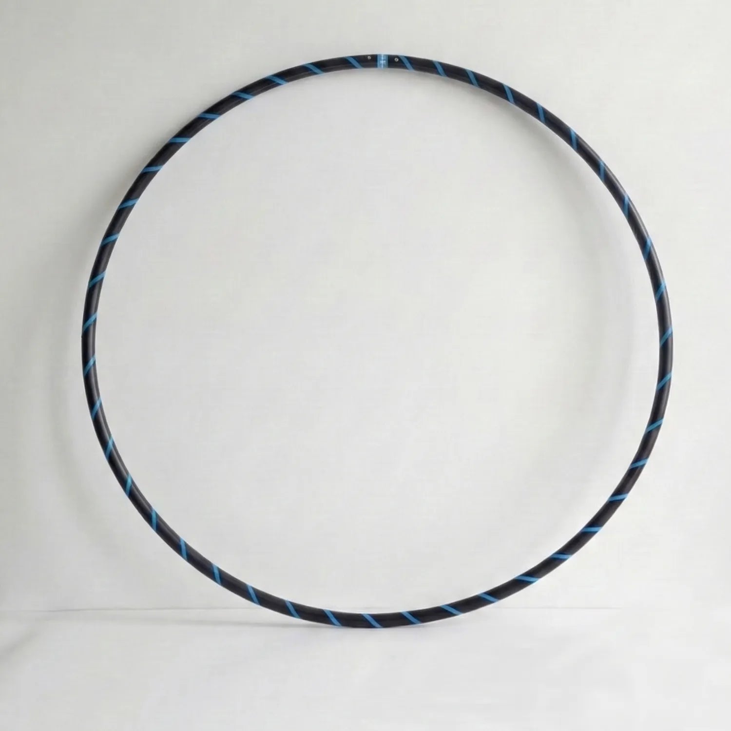 Studio shot of the B108 DESIGN weighted fitness hula hoop in obsidian black with an electric blue spiral grip tape pattern against a clean white backdrop.