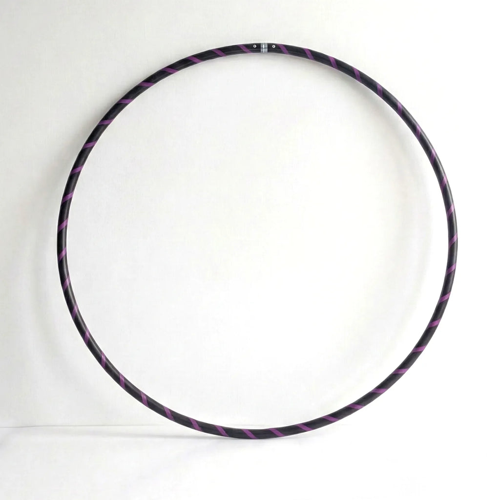 Studio shot of the B108 DESIGN weighted fitness hula hoop in obsidian black with a purple spiral grip tape pattern against a clean white backdrop.