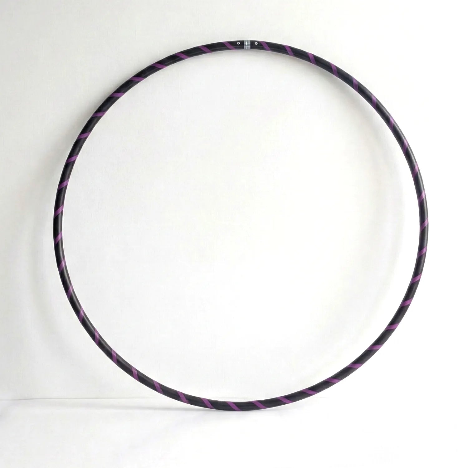 Studio shot of the B108 DESIGN weighted fitness hula hoop in obsidian black with a purple spiral grip tape pattern against a clean white backdrop.