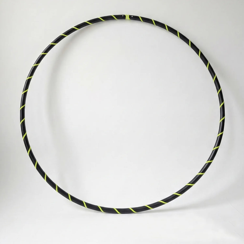 Studio shot of the B108 DESIGN weighted fitness hula hoop in obsidian black with a fluoro yellow spiral grip tape pattern against a clean white backdrop.