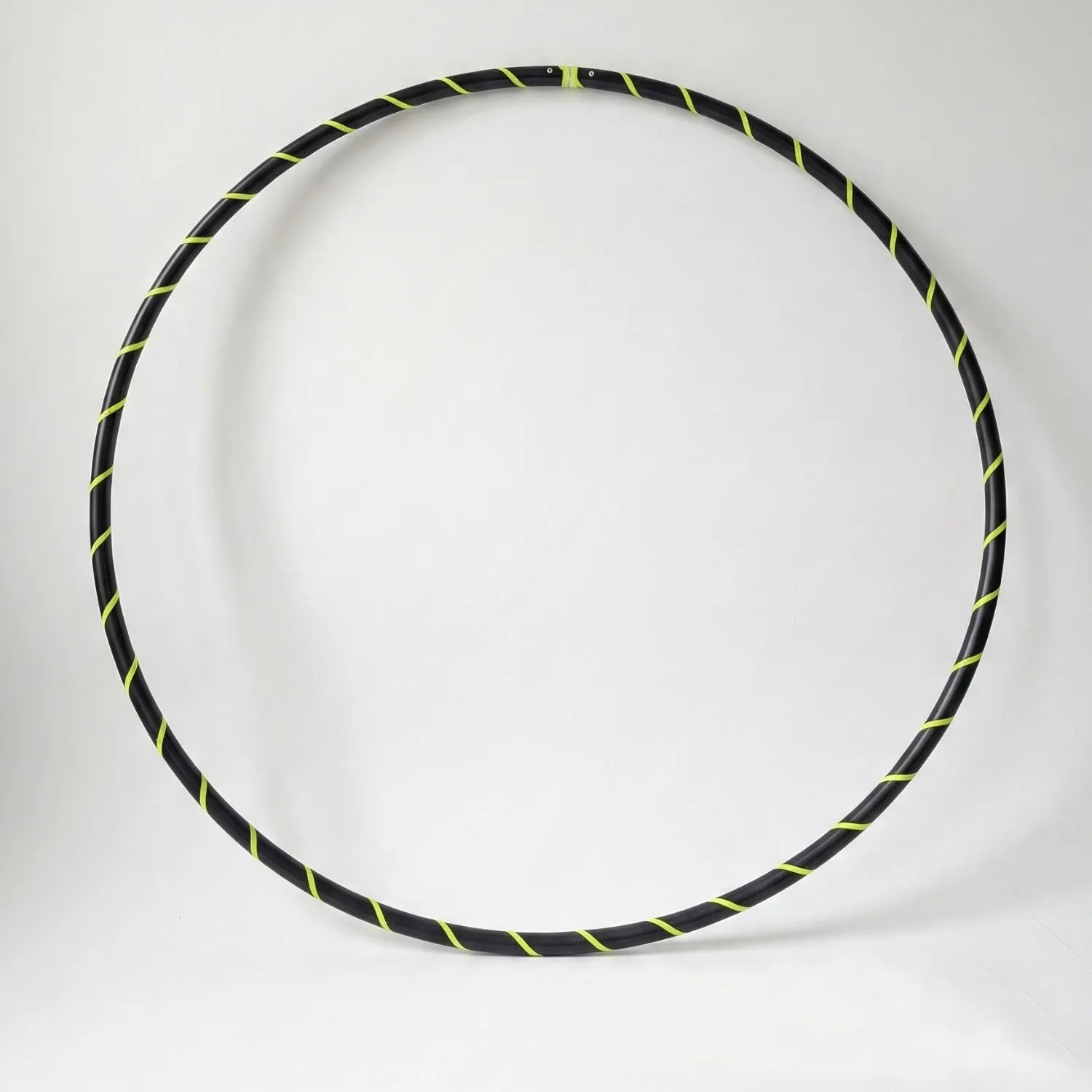 Studio shot of the B108 DESIGN weighted fitness hula hoop in obsidian black with a fluoro yellow spiral grip tape pattern against a clean white backdrop.